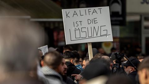 Teilnehmer einer Islamisten-Demo halten ein Plakat mit der Aufschrift "Kalifat ist die Lösung" in die Höhe