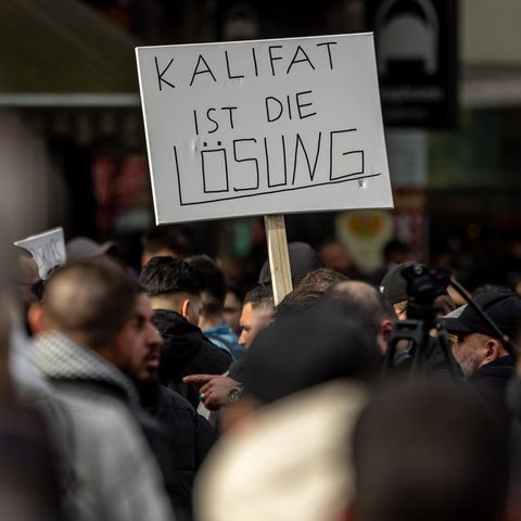 Teilnehmer einer Islamisten-Demo halten ein Plakat mit der Aufschrift "Kalifat ist die Lösung" in die Höhe