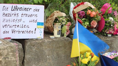 Am Tatort im bayerischen Murnau haben Ukrainer Blumensträuße und eine ukrainische Flagge aufgestellt