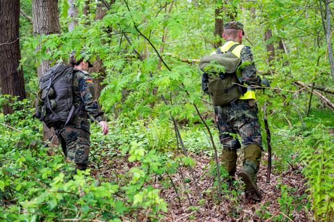 Eine Soldatin und ein Soldat suchen im Wald nach dem vermissten Jungen Arian.