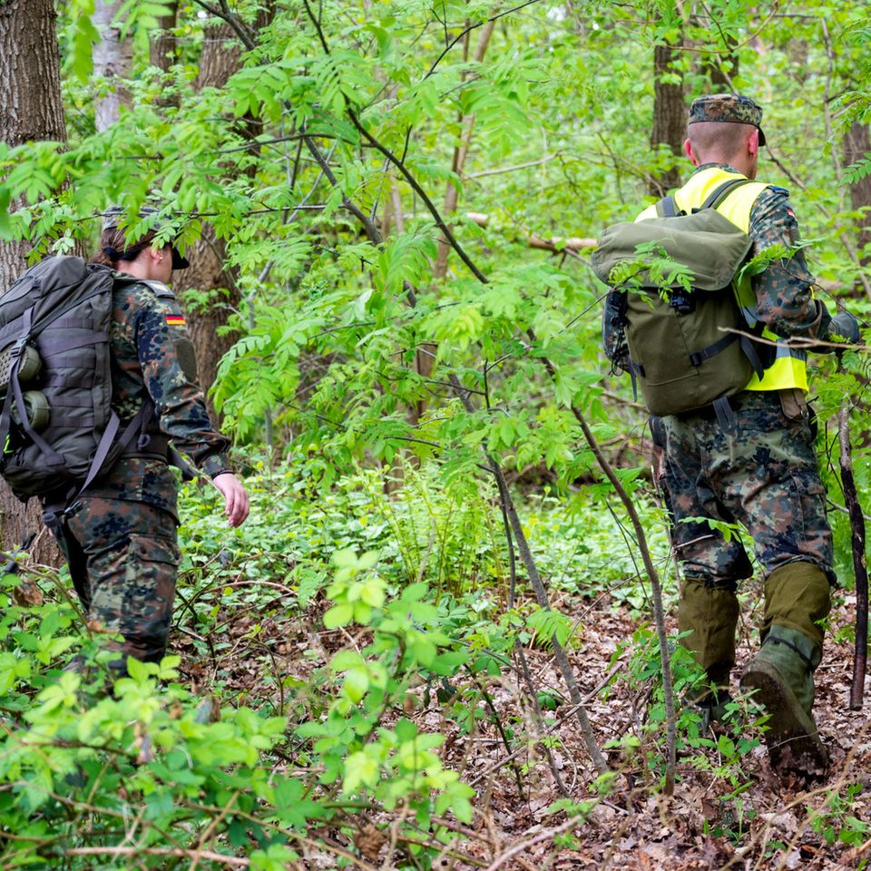 Eine Soldatin und ein Soldat suchen im Wald nach dem vermissten Jungen Arian.