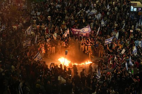 Eine Menschenmenge mit Flaggen Israels steht um ein Feuer herum und fordert Geisel-Freilassungen