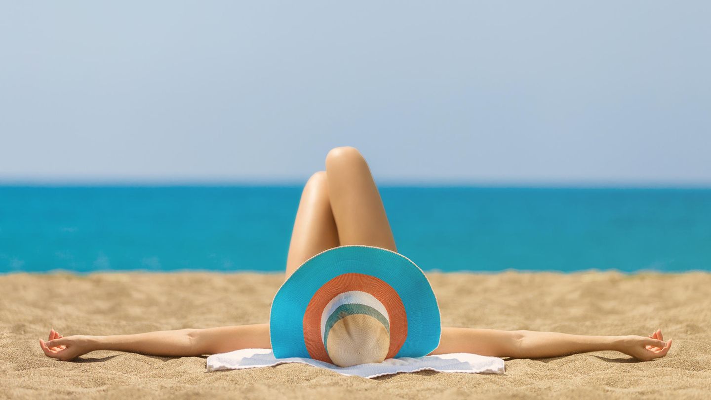 Frau mit Sonnenhut am Strand