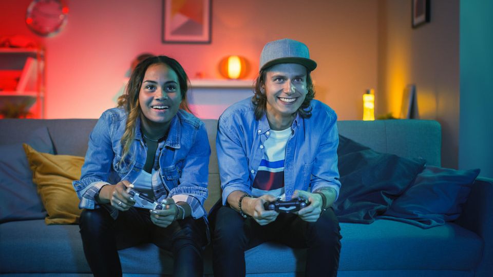 Amazon Gaming Week 2024: Zwei Gamer:innen sitzen auf der Couch und haben Spaß beim Zocken