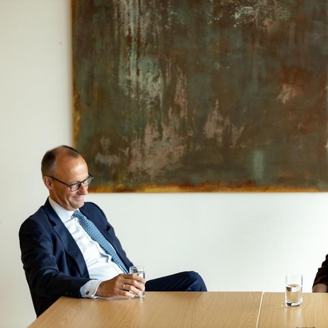 Friedrich Merz und Ricarda Lang sitzen an einem Tisch und lachen