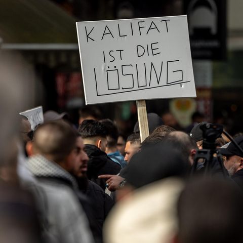 Teilnehmer einer Demonstration tragen ein Plakat mit der Aufschrift "Kalifat ist die Lösung"