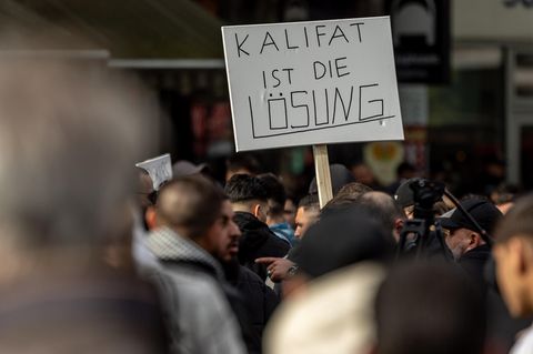 Teilnehmer einer Demonstration tragen ein Plakat mit der Aufschrift "Kalifat ist die Lösung"