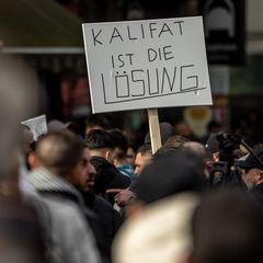 Teilnehmer einer Demonstration tragen ein Plakat mit der Aufschrift "Kalifat ist die Lösung"