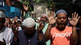 Eine Gruppe Menschen in T-Shirts in Bangladesch wendet die Hände gen Himmel, die Augen geschlossen.