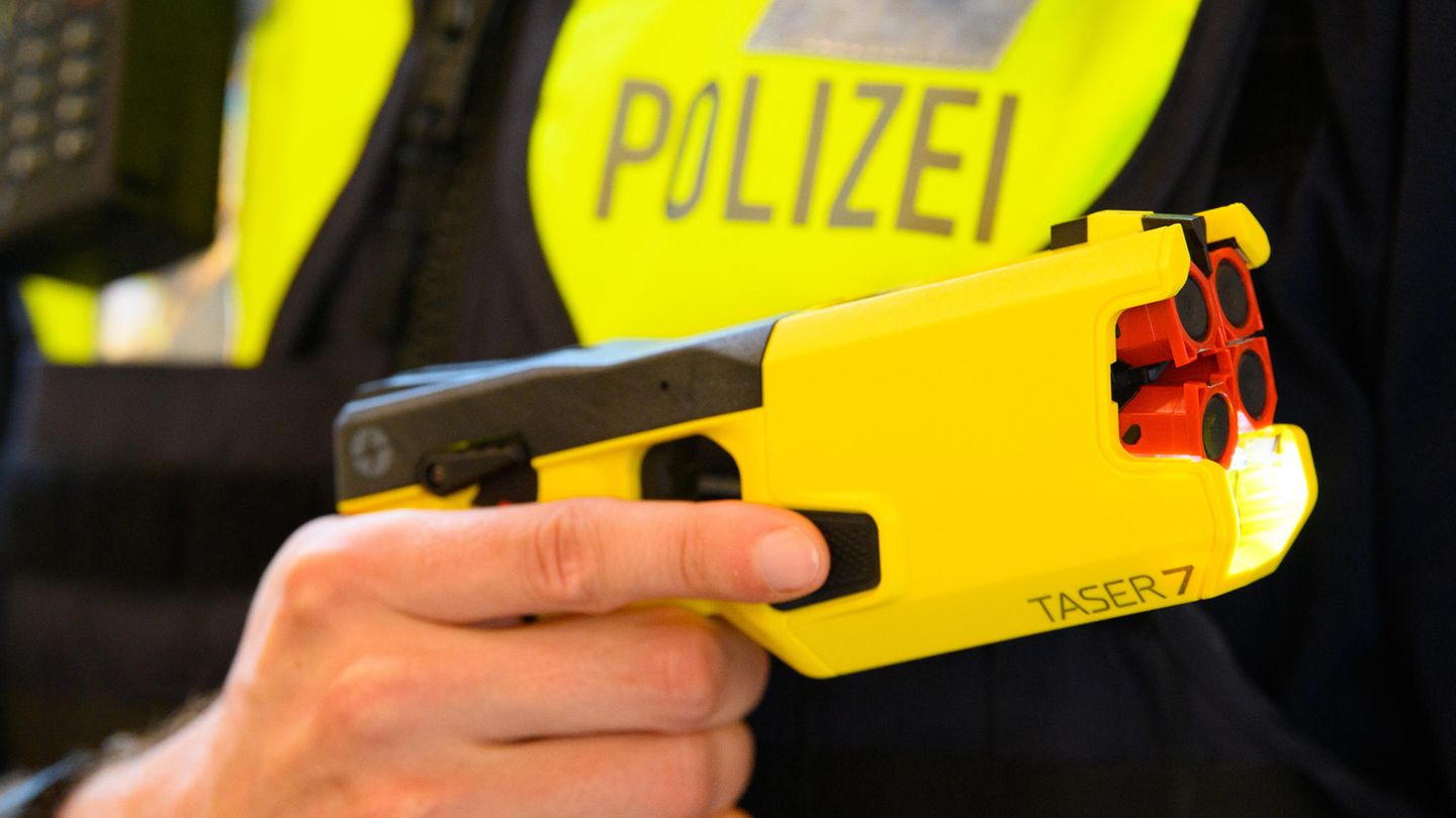 Ein Polizeibeamter hält einen Taser in der Hand (Archivbild)