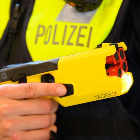 Ein Polizeibeamter hält einen Taser in der Hand (Archivbild)