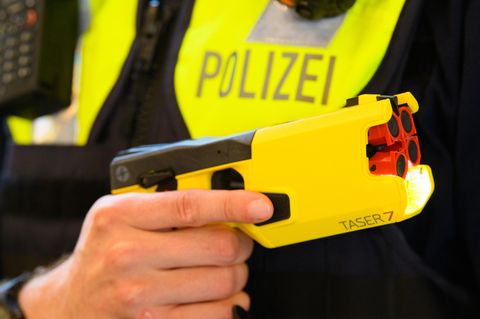 Ein Polizeibeamter hält einen Taser in der Hand (Archivbild)