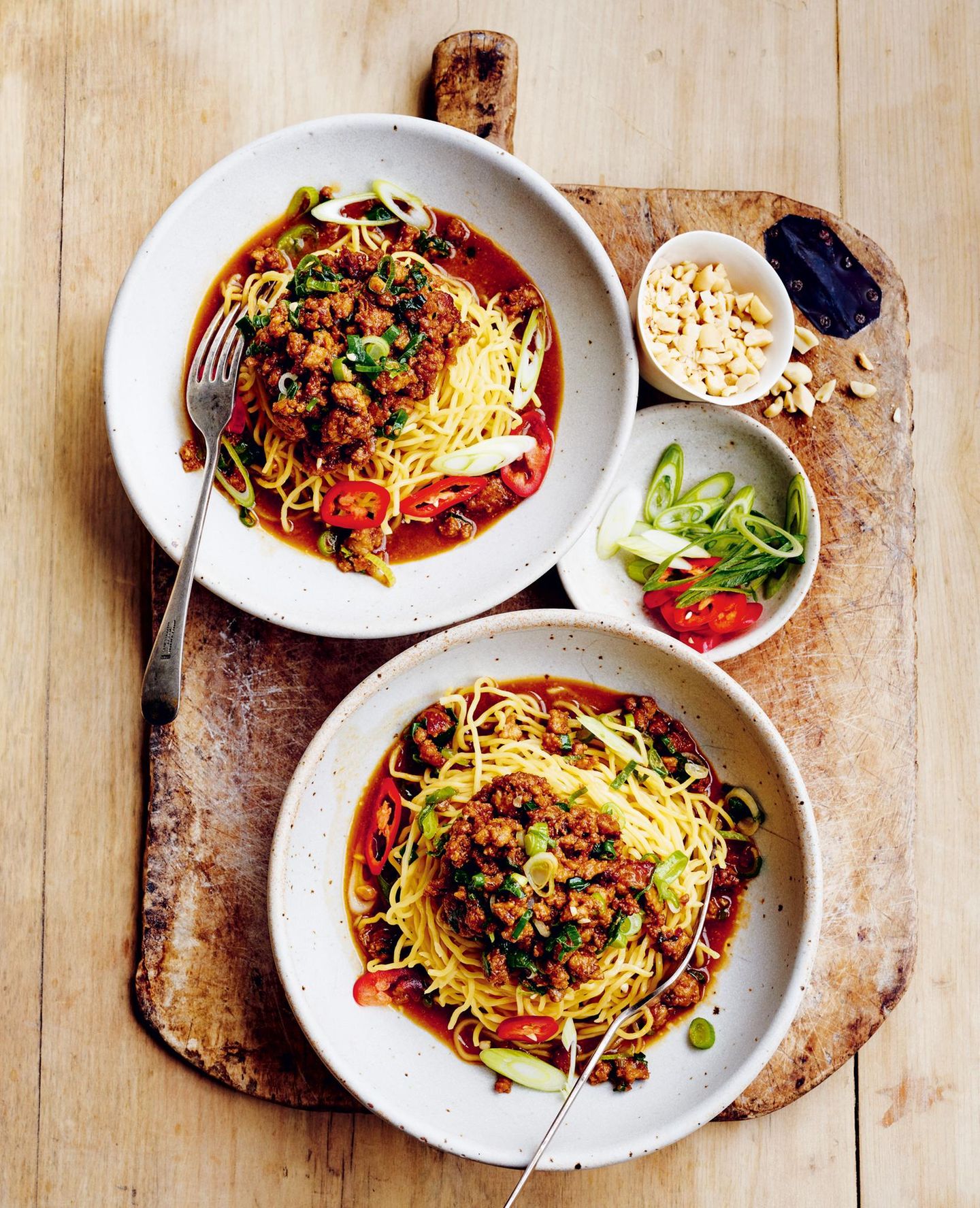 Eiernudeln mit Sauce  400 g frische Eiernudeln  2 Knoblauchzehen, zerdrückt  4 Frühlingszwiebeln, in Ringe geschnitten  500 g Schweine- oder Geflügelhackfleisch  500 ml hochwertige Hühnerbrühe  mehr Frühlingszwiebelringe, in Ringe geschnittene lange rote Chilischote und gehackte, geröstete und gesalzene Erdnüsse zum Servieren     Für die würzige Erdnusssauce  70 g cremige, naturbelassene Erdnussbutter oder helles Tahini 60 ml Hoisin-Sauce  60 ml Sojasauce  2 TL Sesamöl  1 EL fertig gekauftes Chiliöl   1 EL Honig     Die Nudeln nach den Angaben auf der Packung kochen. Unter kaltem Wasser abschrecken, abgießen und beiseite stellen.  Für die Erdnusssauce Erdnussbutter, Hoisinsauce, Sojasauce, Sesamöl, Chiliöl und Honig in einer Schüssel gründlich verschlagen.  Eine große Pfanne bei mittlerer bis starker Hitze aufsetzen.  Die Hälfte der Erdnusssauce, Knoblauch und Frühlingszwiebel hineingeben und 1 Minute anbraten. Hackfleisch hinzugeben und 7–8 Minuten braten, bis es schön braun wird.  Die Brühe in einem kleinen Topf bei schwacher bis mittlerer Hitze in 5 Minuten heiß werden lassen. Die restliche Erdnusssauce einrühren und erhitzen.  Zum Servieren die Erdnusssauce auf Schalen verteilen und die heißen Nudeln dazugeben. Mit Hackfleisch, zusätzlichen Frühlingszwiebelringen, roten Chiliringen und gerösteten Erdnüssen belegen.