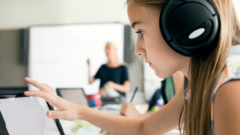Symbolbild für Kehrtwende in Schweden: Ein Mädchen im Unterricht mit Kopfhörern an einem Tablet