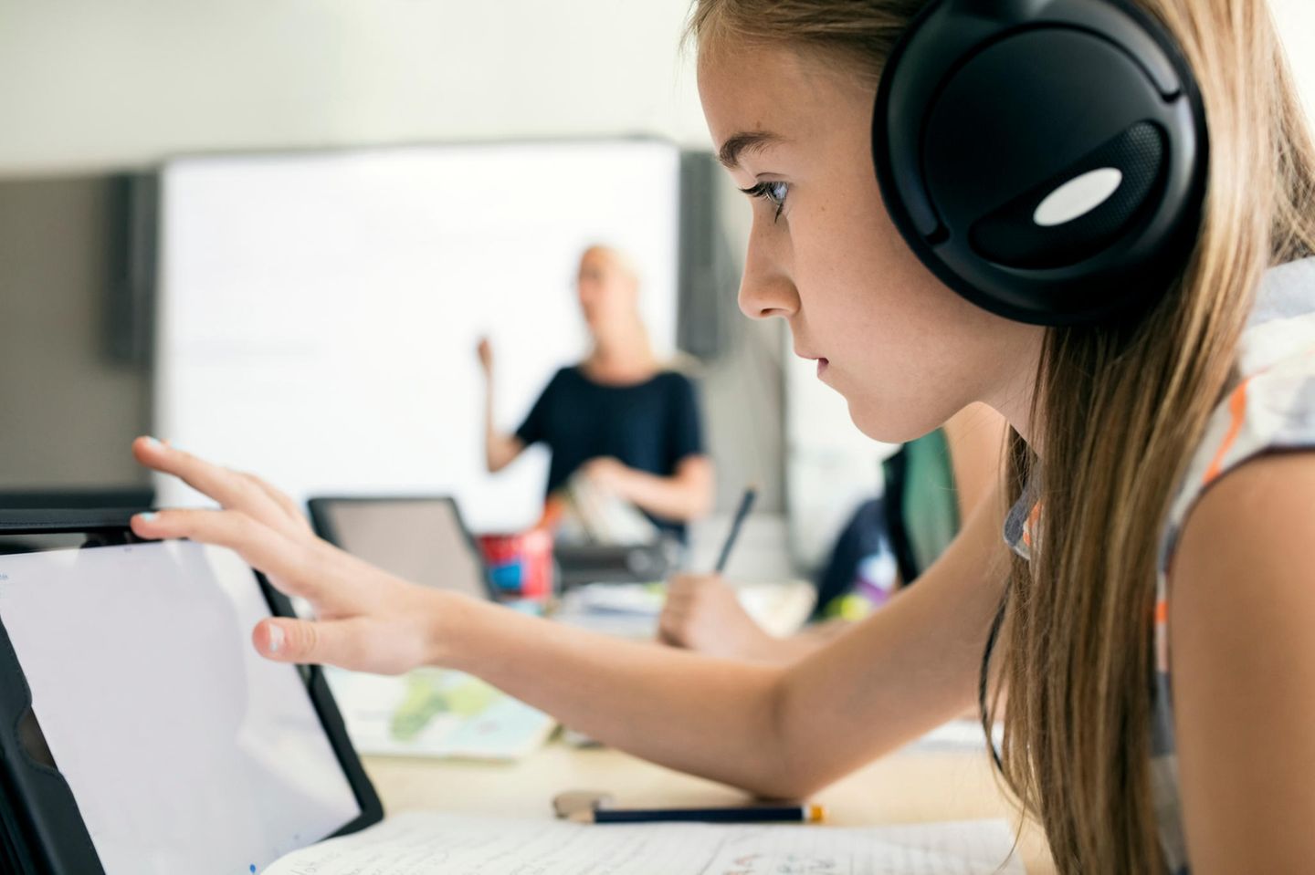 Symbolbild für Kehrtwende in Schweden: Ein Mädchen im Unterricht mit Kopfhörern an einem Tablet