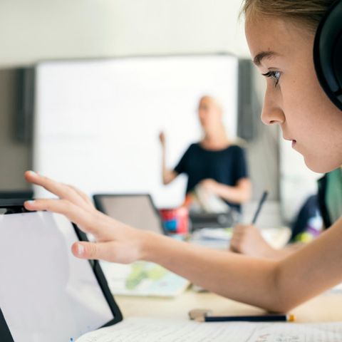 Symbolbild für Kehrtwende in Schweden: Ein Mädchen im Unterricht mit Kopfhörern an einem Tablet