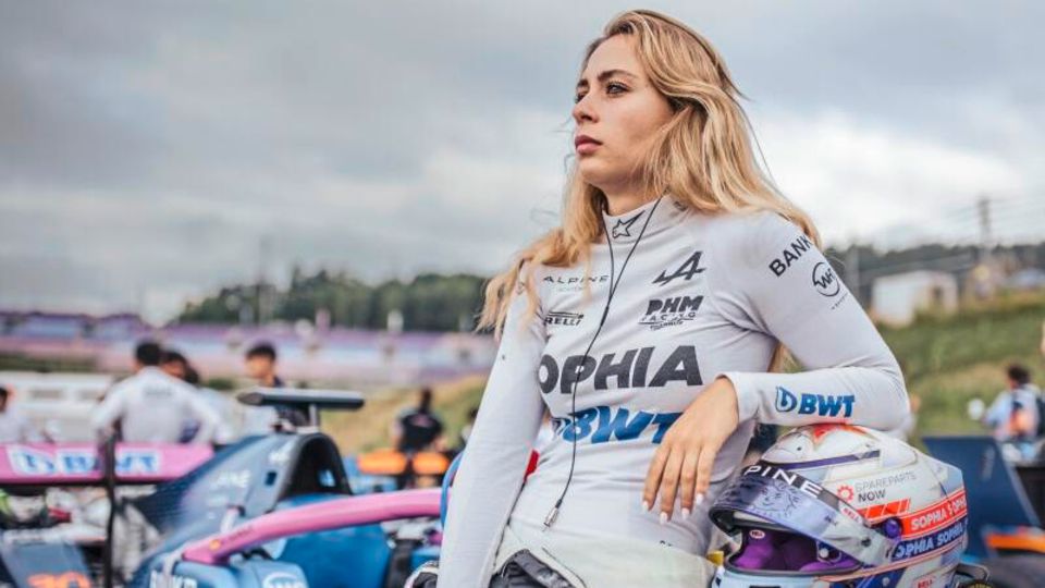 Sophia Flörsch im Rennanzug am Auto