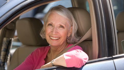 Eine ältere Frau sitzt im Auto am Steuer