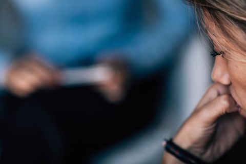 Eine Junge Frau knabbert an ihren Fingernägeln während sie bei einem Therapeuten sitzt