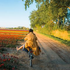 Stress reduzieren: Eine Radfahrerin fährt entlang eines Blumenfeldes