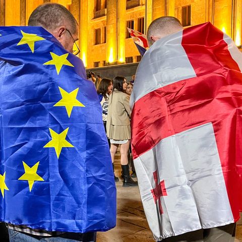In Georgia, one demonstrator is wrapped in an EU flag and the other in a Georgian flag