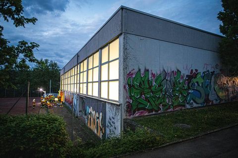 In Remshalden stehen an einer Turnhalle Feuerwehrleute