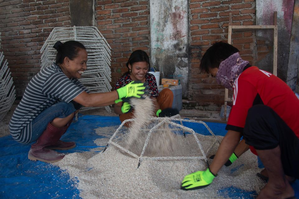 Frauen bestreuen Stahl-Stern mit Korallensand