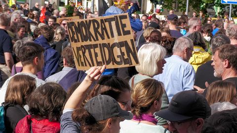 Menschen Demonstrieren nach Angriff auf Matthias Ecke, eine Person hält ein Schild mit der Schrift "Demokratie verteidigen"