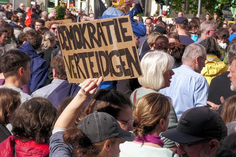 Menschen Demonstrieren nach Angriff auf Matthias Ecke, eine Person hält ein Schild mit der Schrift "Demokratie verteidigen"