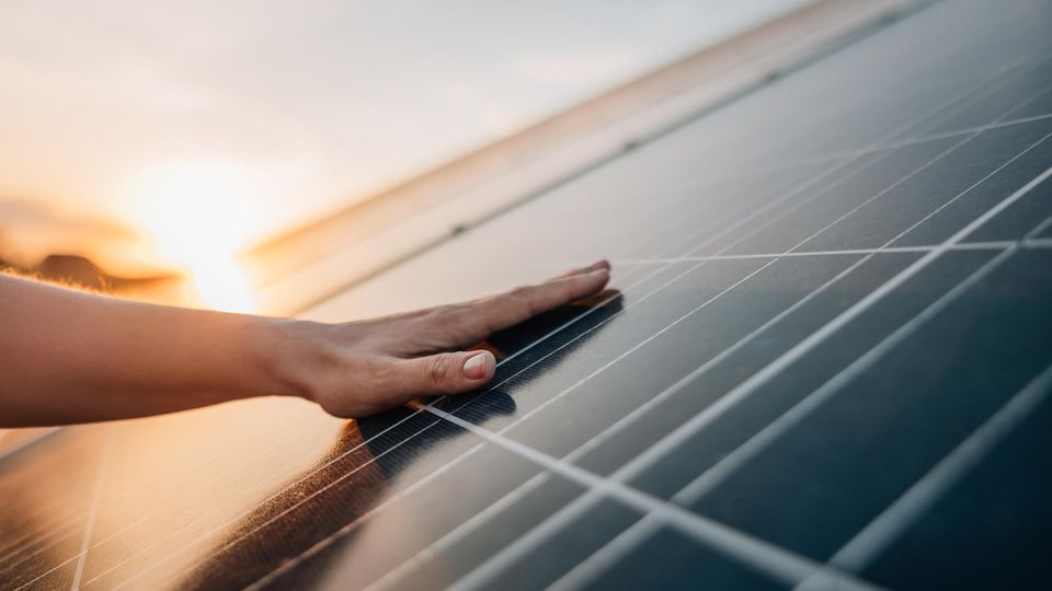 Spielt die Größe beim Kauf eines Balkonkraftwerks eine Rolle? Frauenhand auf Solarpanel.