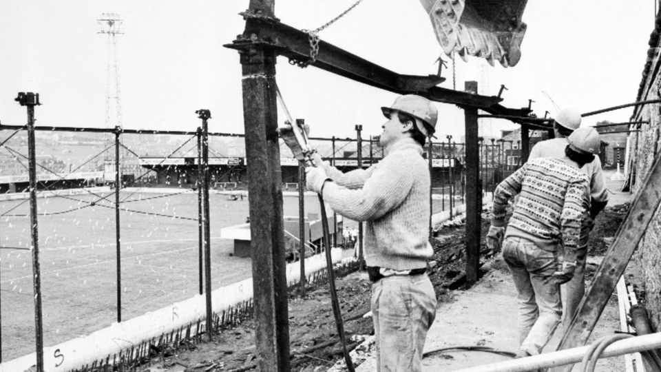 Arbeiter bauen die verkohlten Tribünen-Reste ab