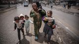 Frauen machen sich mit ihren Kindern zu Fuß auf den Weg raus aus der Stadt. Wer nicht selbst laufen kann, wird getragen.