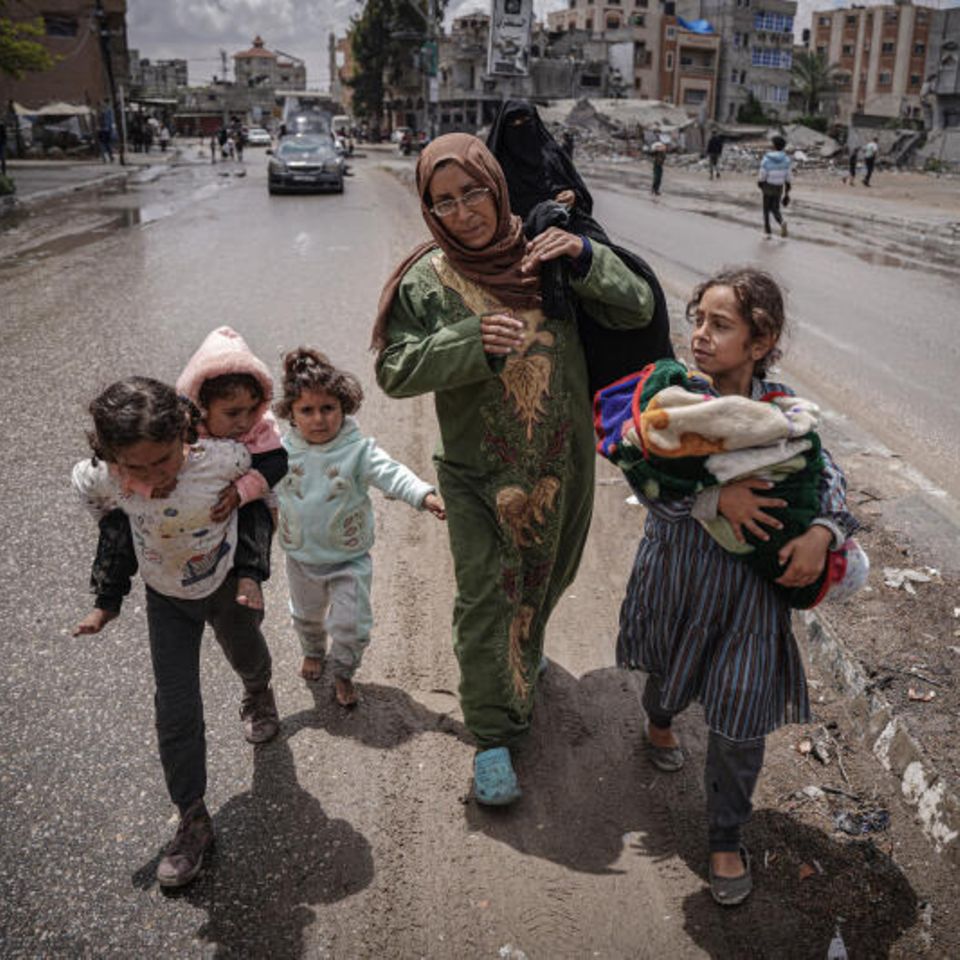 Frauen machen sich mit ihren Kindern zu Fuß auf den Weg raus aus der Stadt. Wer nicht selbst laufen kann, wird getragen.