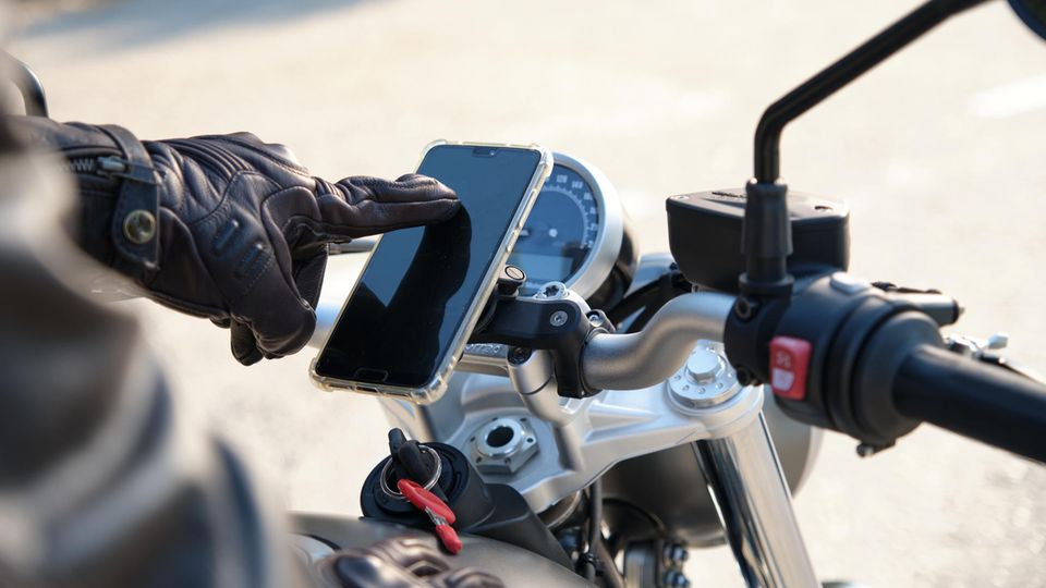 Nahaufnahme einer Person, die das Mobiltelefon auf dem Motorrad benutzt