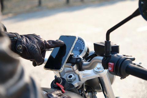 Nahaufnahme einer Person, die das Mobiltelefon auf dem Motorrad benutzt