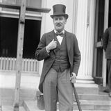 Howard Carter in Frack mit Zylinderhut steht vor dem Weißen Haus