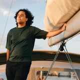 Ramin freut sich, nachdem die Segelreise wirklich begonnen hat. Er steht am Segel und genießt die Sonne