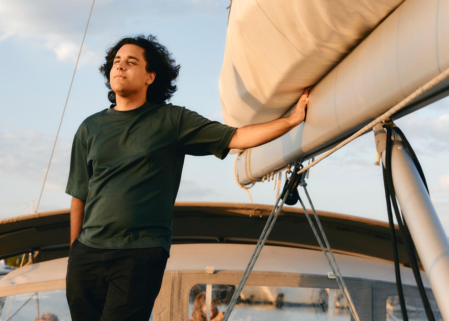 Ramin freut sich, nachdem die Segelreise wirklich begonnen hat. Er steht am Segel und genießt die Sonne