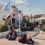 Ein kleiner Platz am Rande eines Hafens. Das Gepäck von Reisenden liegt in der Mitte.