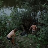 Zwei Kinder steigen in Badekleidung in die Böschung an einem Fluss