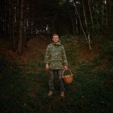 Ein junger Mann in Militäruniform und einem Weidekorb in der Hand.