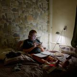 Eine ältere Frau liegt im dunkel in einem Bett.