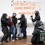 Polizisten räumen den besetzten Audimax der Universität Leipzig. Auf einem Plakat steht in roter Farbe "Uni-Besetzung gegen Genozid". Nach Angaben der Hochschule sollen 50 bis 60 pro-palästinensische Aktivisten an der Protestaktion beteiligt gewesen seien.