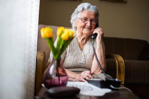 Eine ältere Dame nutzt ein Festnetz-Telefon – beispielsweise um die Telefonauskunft anzurufen
