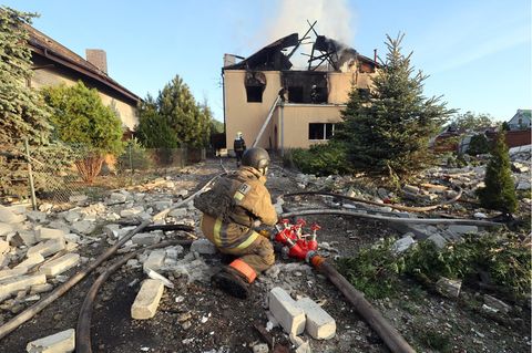 Nach einem russischen Raketenangriff im Nordosten der Ukraine versucht ein Feuerwehrmann den Brand in einem Haus zu löschen.