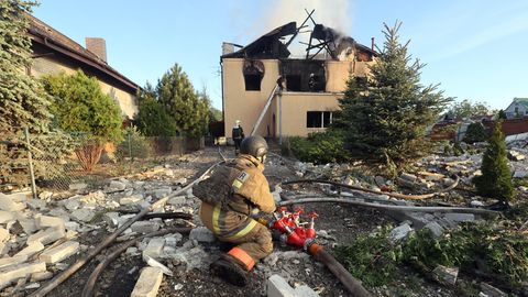 Nach einem russischen Raketenangriff im Nordosten der Ukraine versucht ein Feuerwehrmann den Brand in einem Haus zu löschen.
