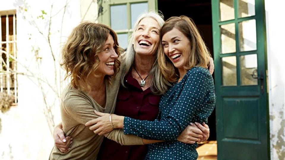 Drei Frauen umarmen einander lächelnd