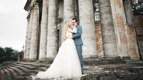 Hochzeitspaar steht auf einer Treppe vor Säulen