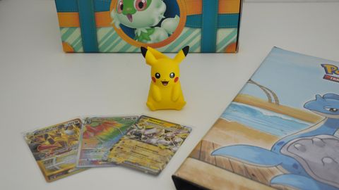 Pokemon-Karten liegen auf einem Tisch mit einem Album und Pikachu
