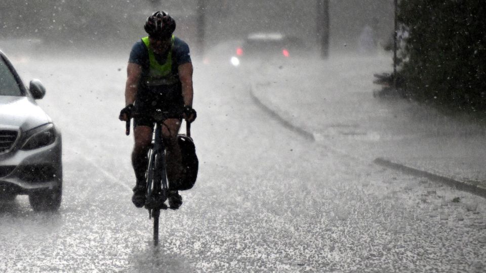 Wetterextreme am 02.05.2024, Nordrhein-Westfalen, Köln: Ein Radfahrer fährt durch einen Hagelsturm